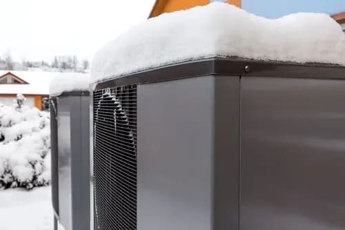 Heat pump unit operating in winter snow outside a New York home